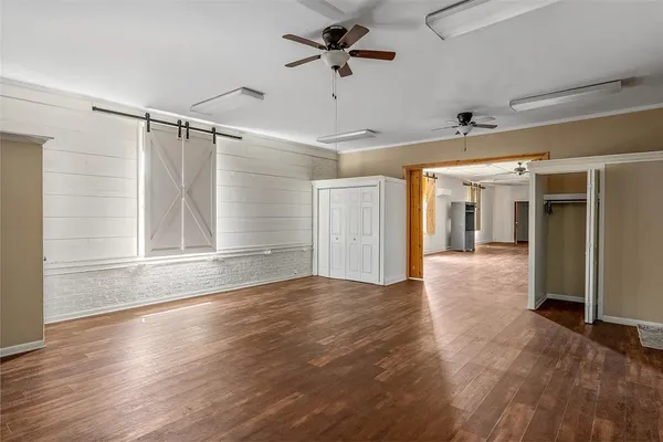 a view of a livingroom with wooden floor a ceiling fan and windows