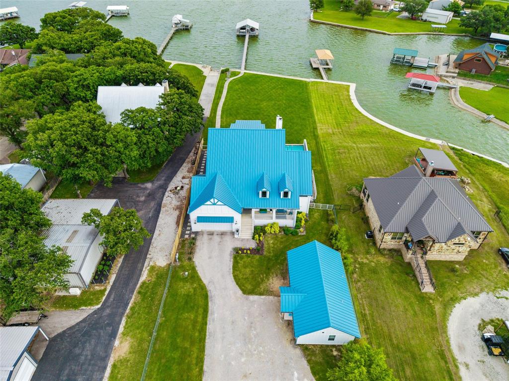 6625 Sandy Beach Road Azle, TX 76020 - Photo 38 of 40 Aerial view showcases direct shoreline access with private dock extending into the lake. Main residence, guest house, detached garage, landscaped lawn areas, and waterfront improvements are visible throughout the property boundaries.