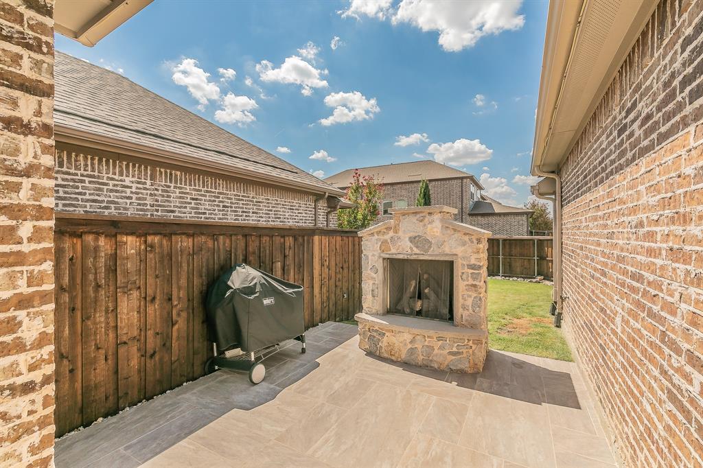 1205 Ivy Charm Way Arlington, TX 76005 - Photo 33 of 40 Outdoor patio featuring a stone-clad fireplace, tile flooring, and a wood privacy fence