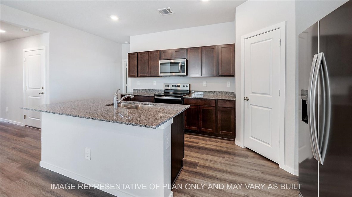 5539 Harriet Street Bryan, TX 77807 - Photo 6 of 17 a kitchen with stainless steel appliances granite countertop a refrigerator a sink a stove a microwave and island