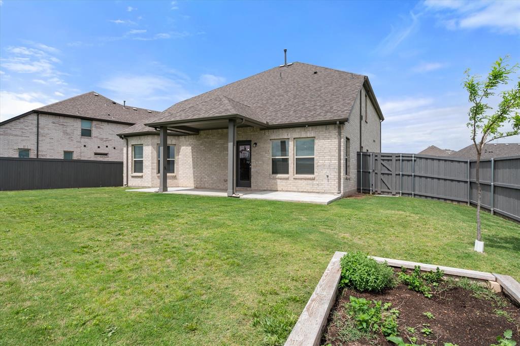 6910 Prairieside Trail Venus, TX 76084 - Photo 36 of 40 The property features a spacious backyard with a well-maintained lawn and a raised garden bed