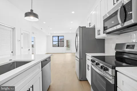 a kitchen with stainless steel appliances granite countertop a refrigerator a stove and a sink with wooden floor