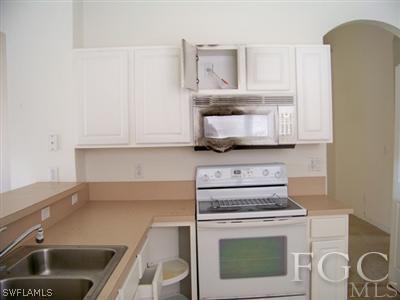 9329 Chestnut Tree Loop, Unit Q Fort Myers, FL 33967 - Photo 3 of 8 a kitchen with granite countertop a stove a sink and a microwave