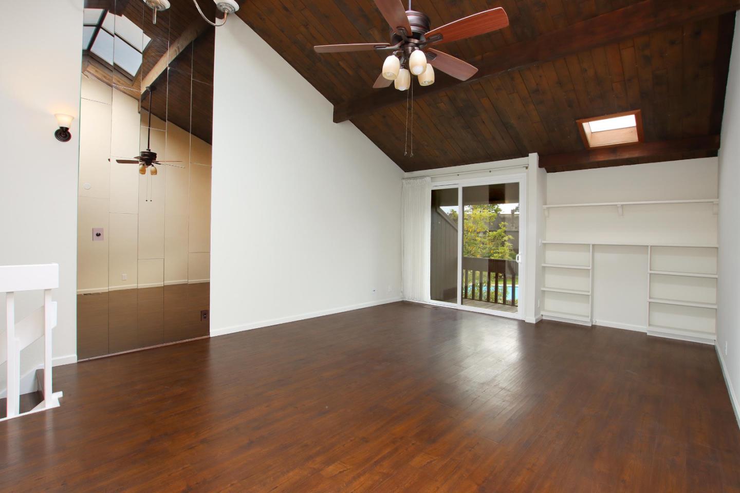 103 Shelter Lagoon Drive Santa Cruz, CA 95060 - Photo 11 of 39 an empty room with wooden floor chandelier fan and windows