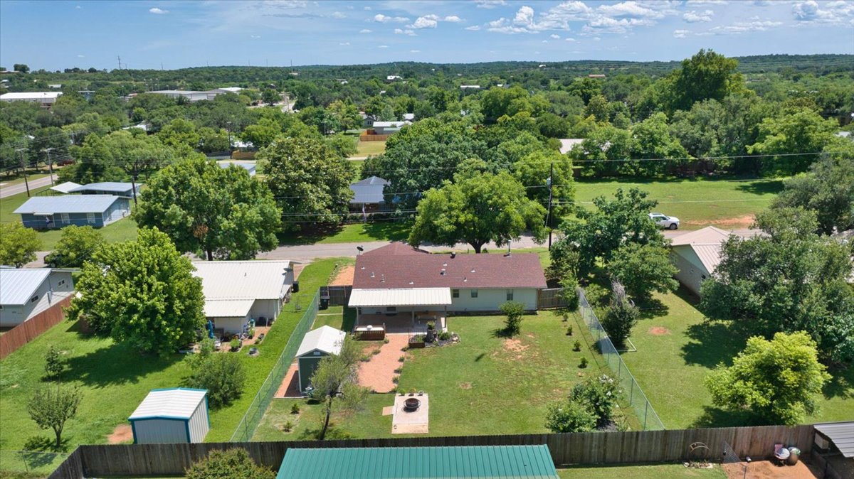 1236 Martin Street Mason, TX 76856 - Photo 33 of 40 An aerial perspective reveals a charming residence nestled among verdant trees and a spacious yard.