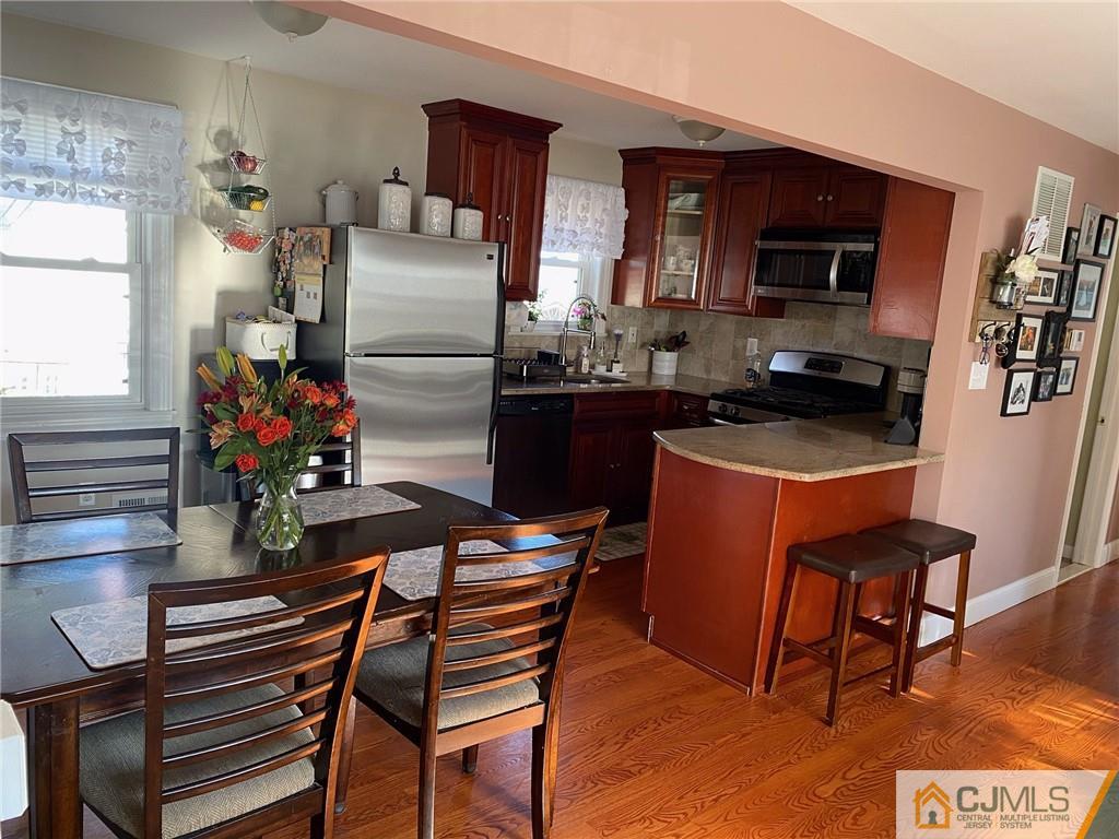 200 New Dover Road Colonia, NJ 07067 - Photo 4 of 14 a kitchen with stainless steel appliances granite countertop a stove a refrigerator a sink a dining table and chairs