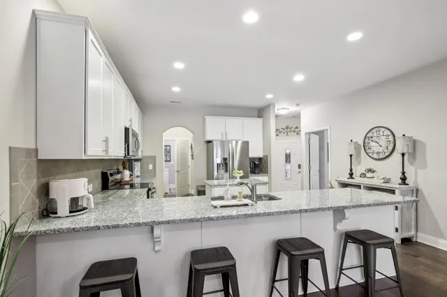 a kitchen with granite countertop white cabinets and chairs
