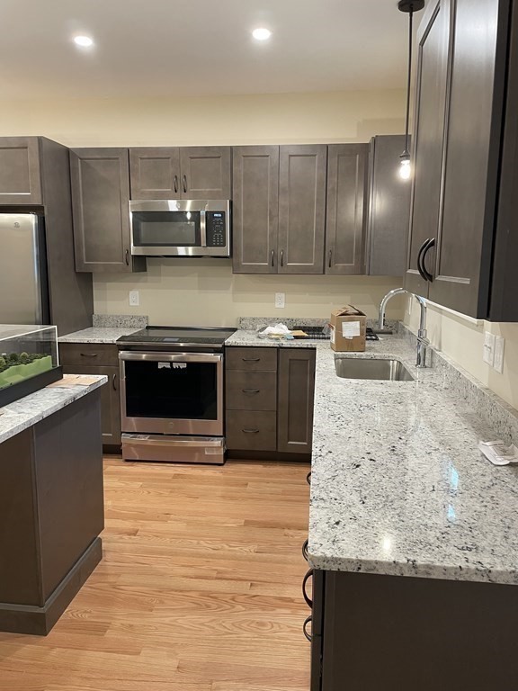 3 Powell Street, Unit B Devens, MA 01434 - Photo 10 of 28 a kitchen with stainless steel appliances granite countertop a sink a stove and cabinets