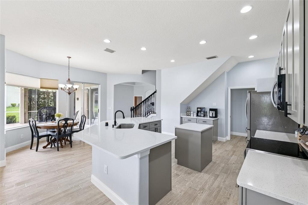 13049 Thoroughbred Drive Dade City, FL 33525 - Photo 14 of 52 a kitchen with stainless steel appliances kitchen island a stove a refrigerator a dining table and chairs with wooden floor