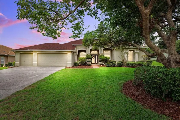 a front view of a house with a garden and trees