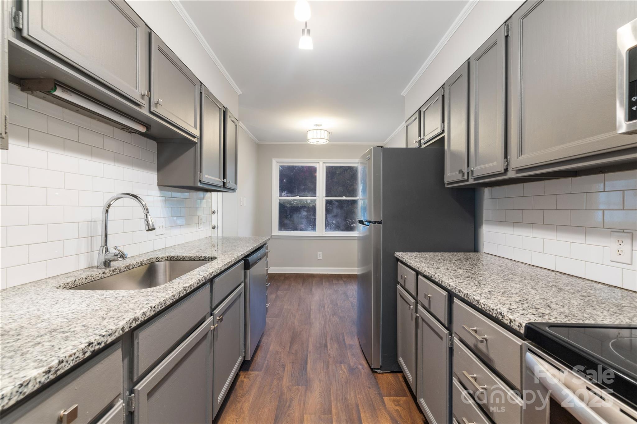 a kitchen with granite countertop stainless steel appliances window a sink and a counter space