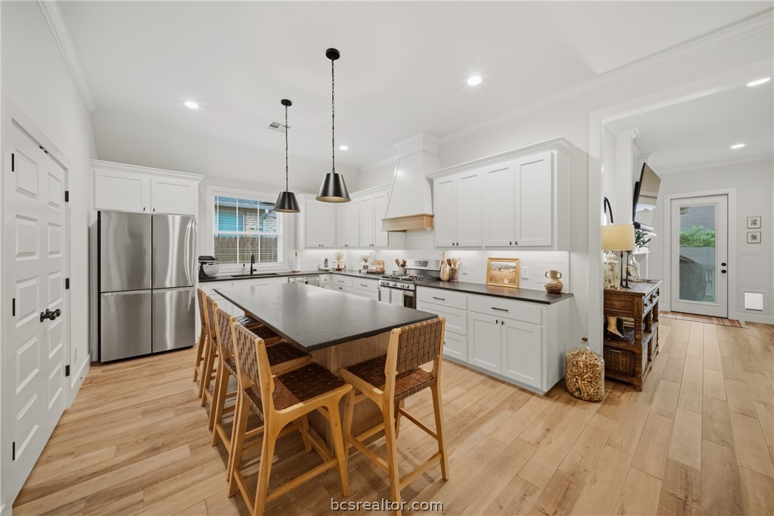 3520 Fairhope Way Bryan, TX 77808 - Photo 10 of 39 a kitchen with stainless steel appliances kitchen island granite countertop a refrigerator a stove a sink dishwasher and white cabinets with wooden floor