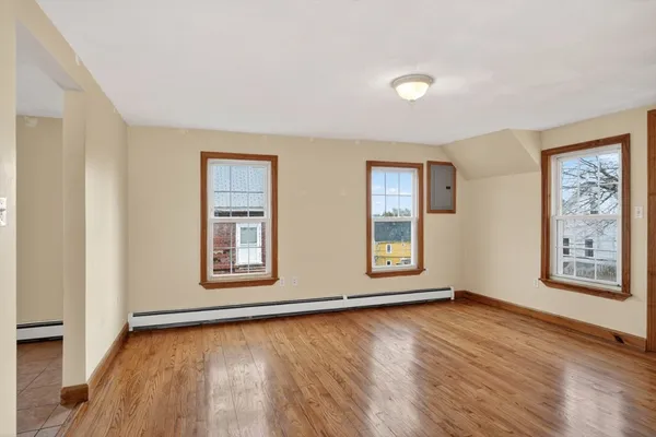 a view of an empty room with window and wooden floor