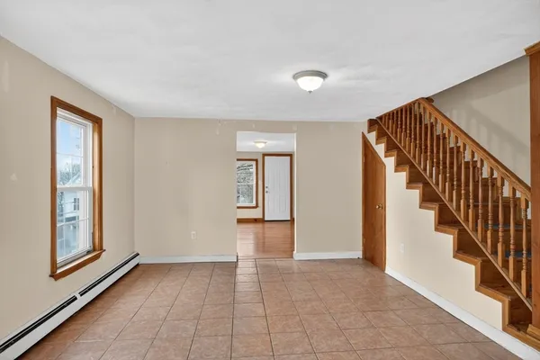 a view of an empty room with wooden floor and stairs