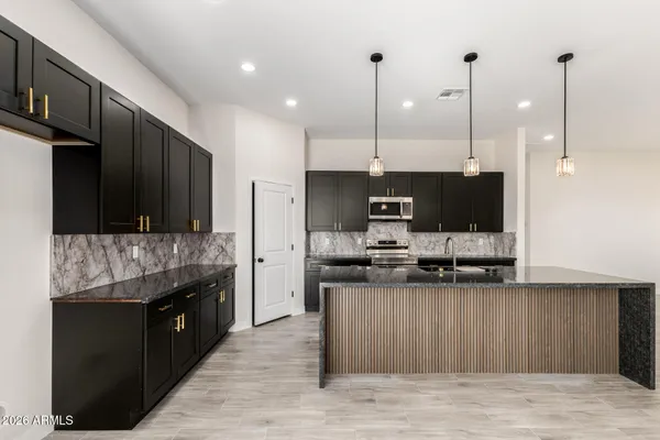 a kitchen with stainless steel appliances kitchen island granite countertop a stove a sink and a refrigerator