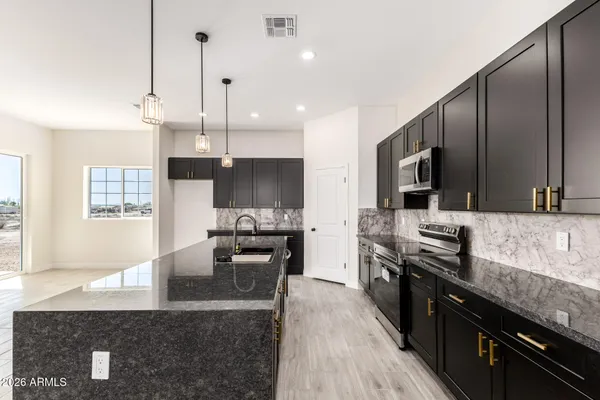 a large kitchen with granite countertop a stove top oven a sink dishwasher a dining table and chairs with wooden floor