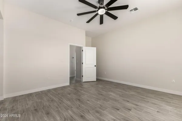 an empty room with wooden floor closet and fan