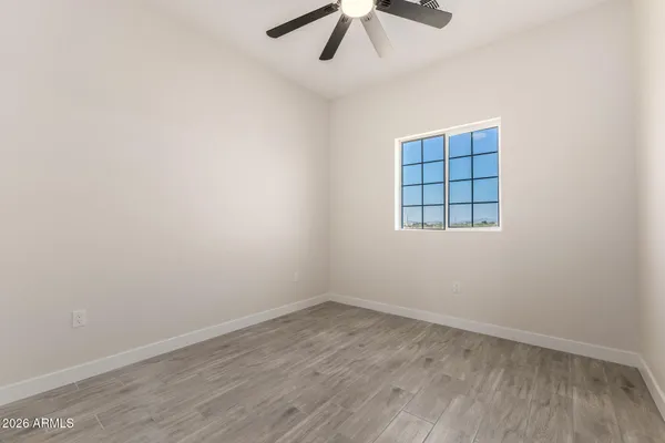 an empty room with wooden floor fan and windows