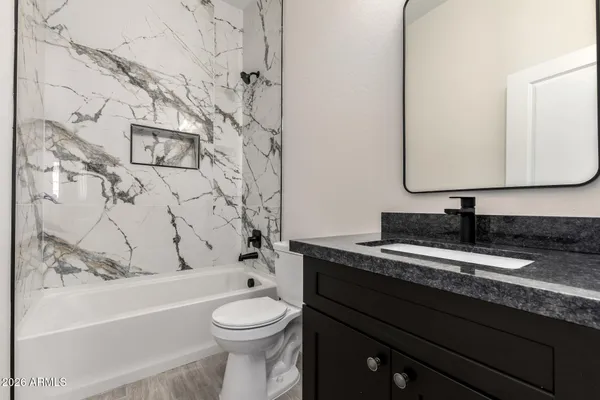 a bathroom with a granite countertop bathtub sink vanity mirror and toilet