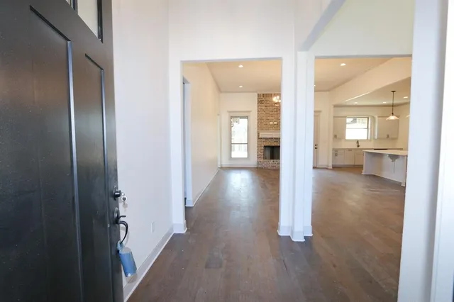 a view of a hallway with wooden floor windows and a kitchen