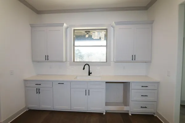 a kitchen with white cabinets appliances a sink and a window