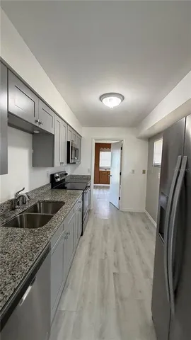 a kitchen with stainless steel appliances granite countertop a sink refrigerator and cabinets