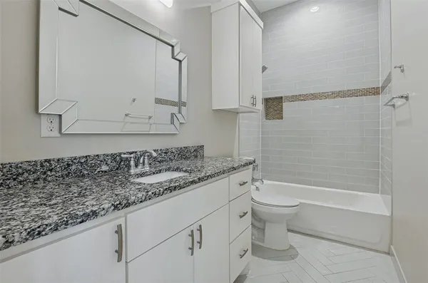 a bathroom with a granite countertop sink a toilet and bathtub