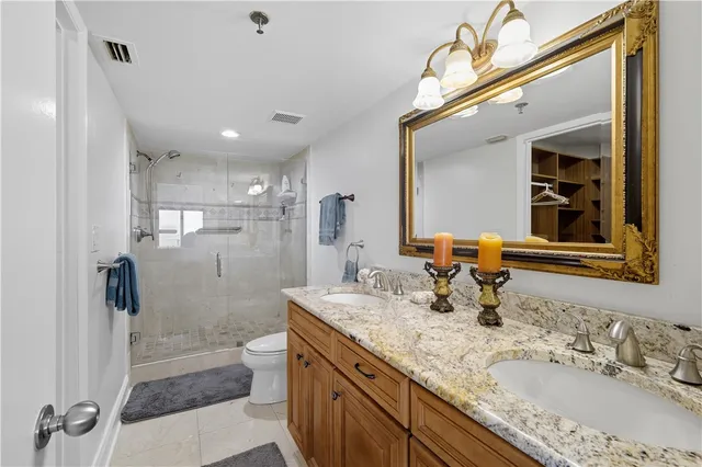 a bathroom with a granite countertop sink a toilet a mirror and shower