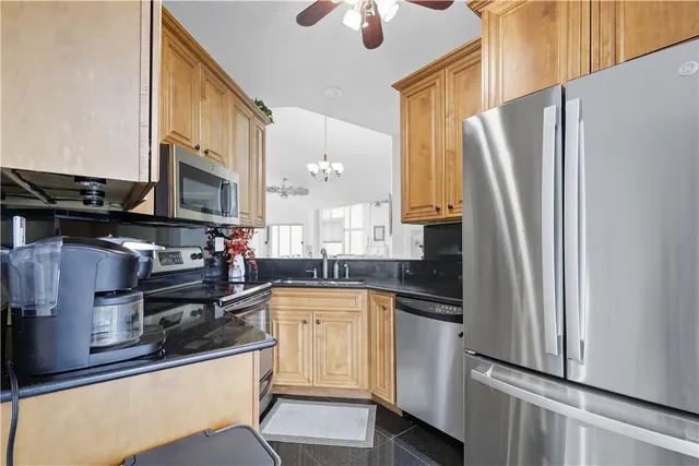a kitchen with stainless steel appliances granite countertop a refrigerator a stove and a sink with wooden floor