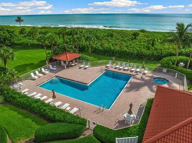 a view of a patio with lawn chairs floor to ceiling window and pool