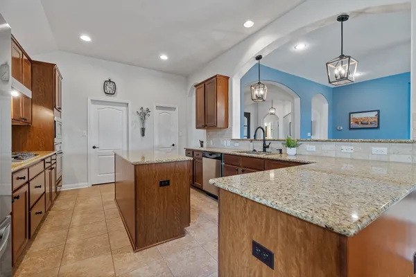 a large kitchen with kitchen island a large counter top space stainless steel appliances and cabinets