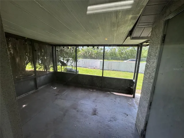 a view of an empty room with a floor to ceiling window next to a yard