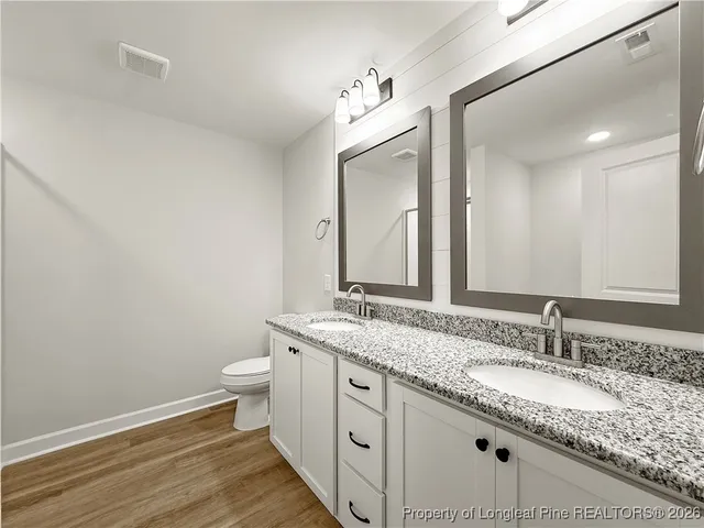 a large white bathroom with a granite countertop sink and a mirror