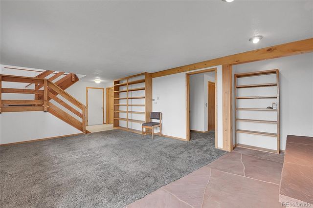 a view of an empty room with stairs and a ceiling fan