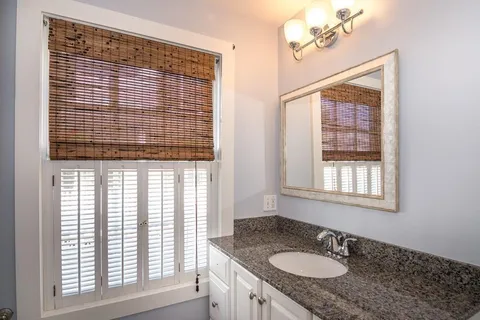 a bathroom with a granite countertop sink and a window