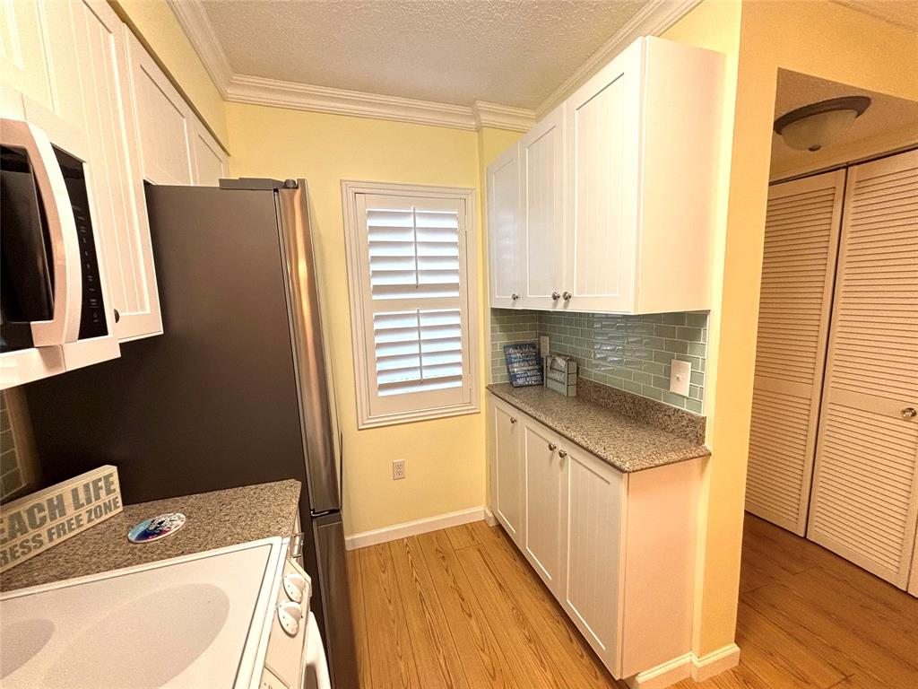 2236 North Cypress Bend Drive, Unit 304 Pompano Beach, FL 33069 - Photo 9 of 17 a kitchen with a sink a refrigerator and window