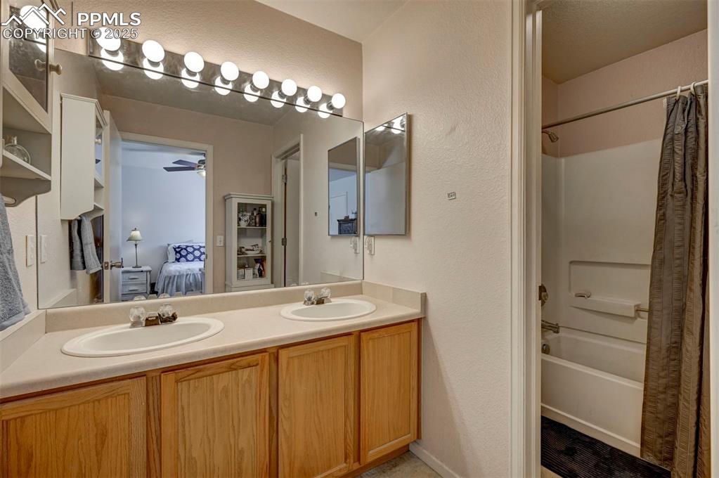12593 Pine Valley Circle Peyton, CO 80831 - Photo 11 of 17 Bathroom featuring ensuite bath, double vanity, shower / bath combo with shower curtain, a textured wall, and a ceiling fan