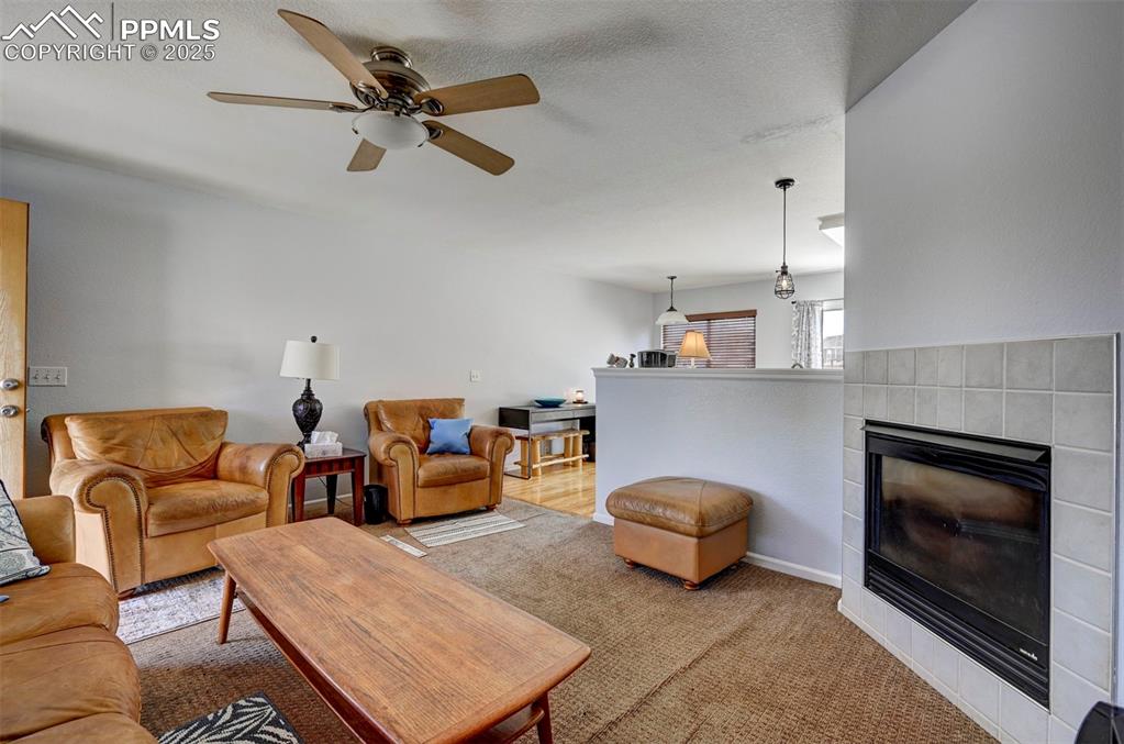 12593 Pine Valley Circle Peyton, CO 80831 - Photo 8 of 17 Carpeted living area featuring a ceiling fan and a tile fireplace