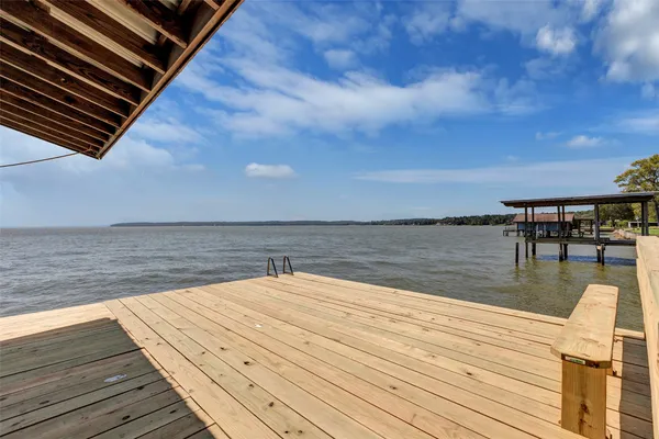 a view of a roof deck with table and chairs a barbeque with wooden floor and fence