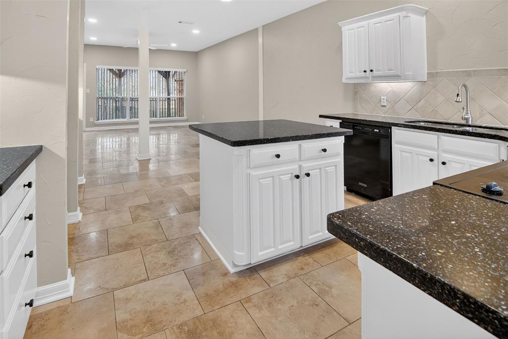 a kitchen with granite countertop a sink a stove and cabinets