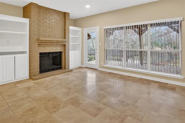 a view of an empty room with a fireplace and a window