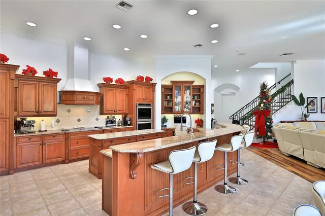 a kitchen with stainless steel appliances kitchen island granite countertop a table chairs and a sink
