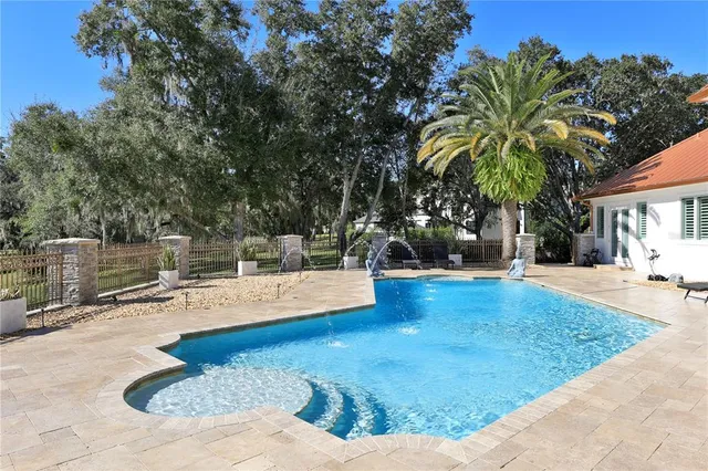 a view of swimming pool with seating space and trees in the background