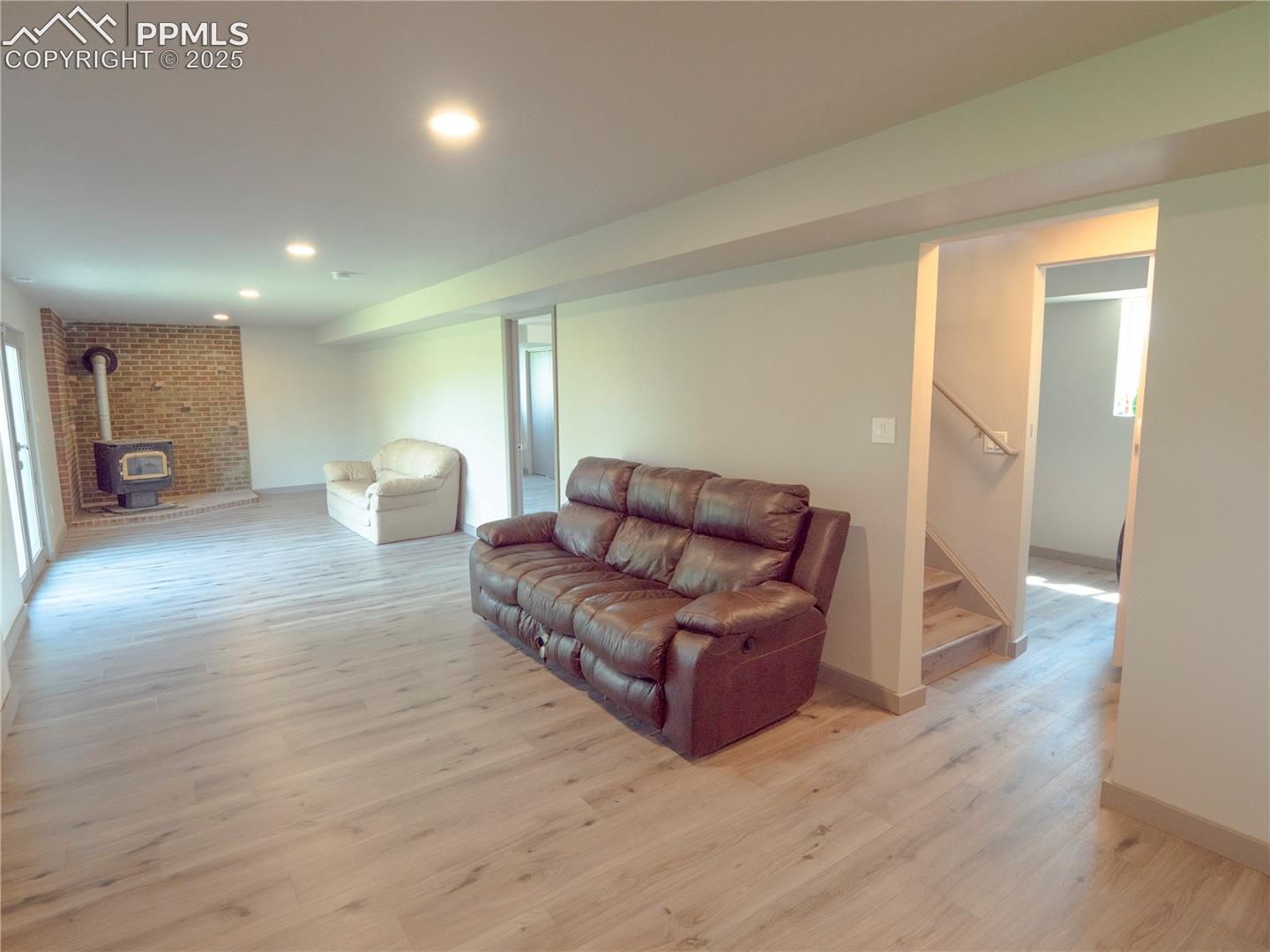 4130 Walker Road Colorado Springs, CO 80908 - Photo 31 of 39 Living room with a wood stove, light wood-style flooring, stairway, and recessed lighting