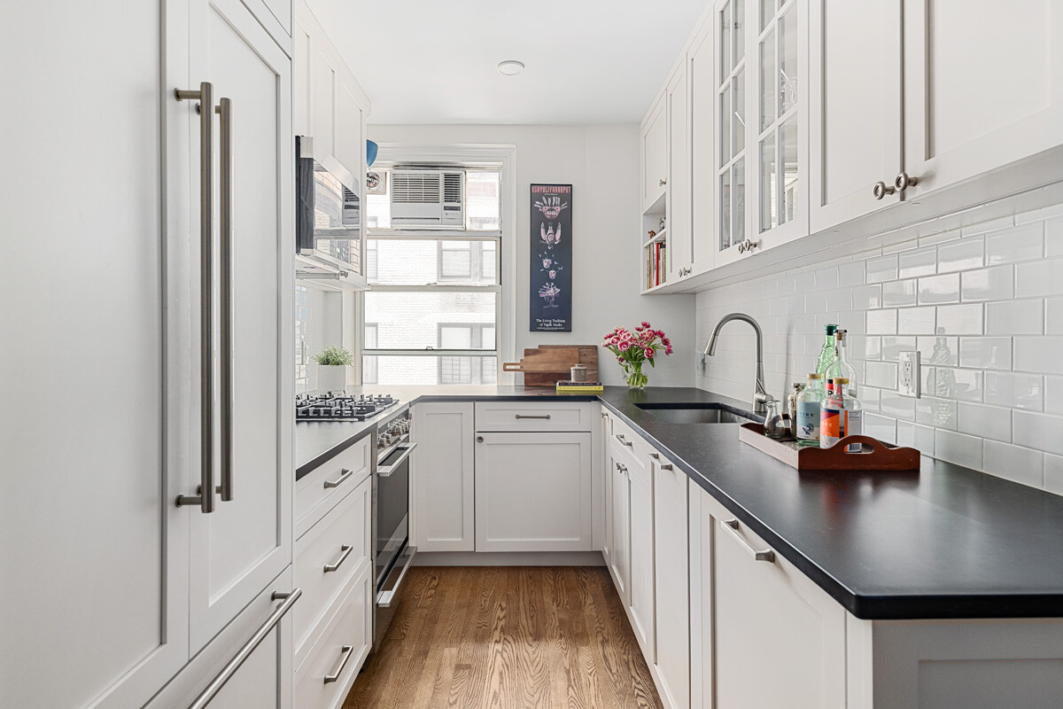 215 East 73rd Street, Unit 2A Manhattan, NY 10021 - Photo 4 of 20 a kitchen with white cabinets and appliances