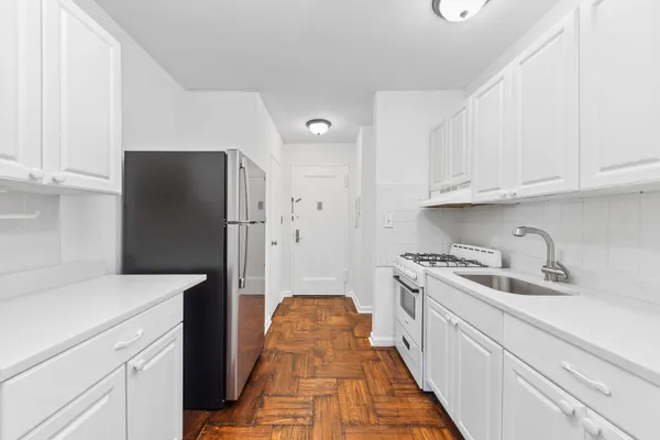 a kitchen with white cabinets and refrigerator