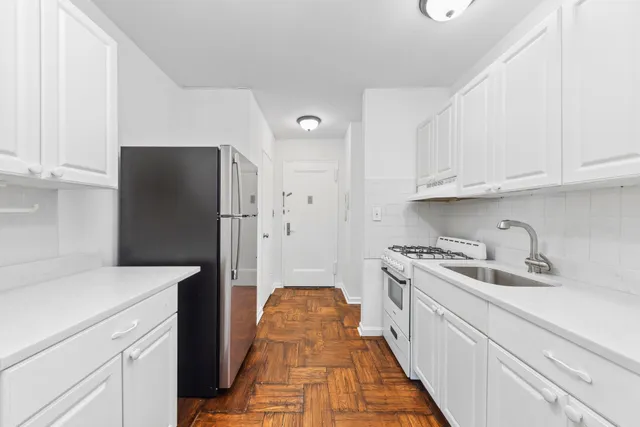 a kitchen with white cabinets and refrigerator