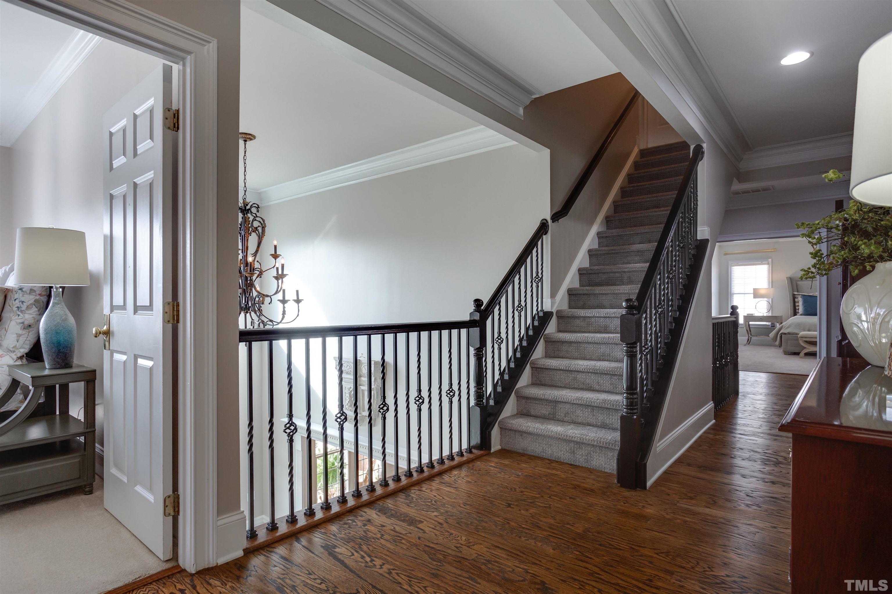 11313 Ridgegate Drive Raleigh, NC 27617 - Photo 69 of 82 a view of staircase with lots of frames on wall and wooden floor
