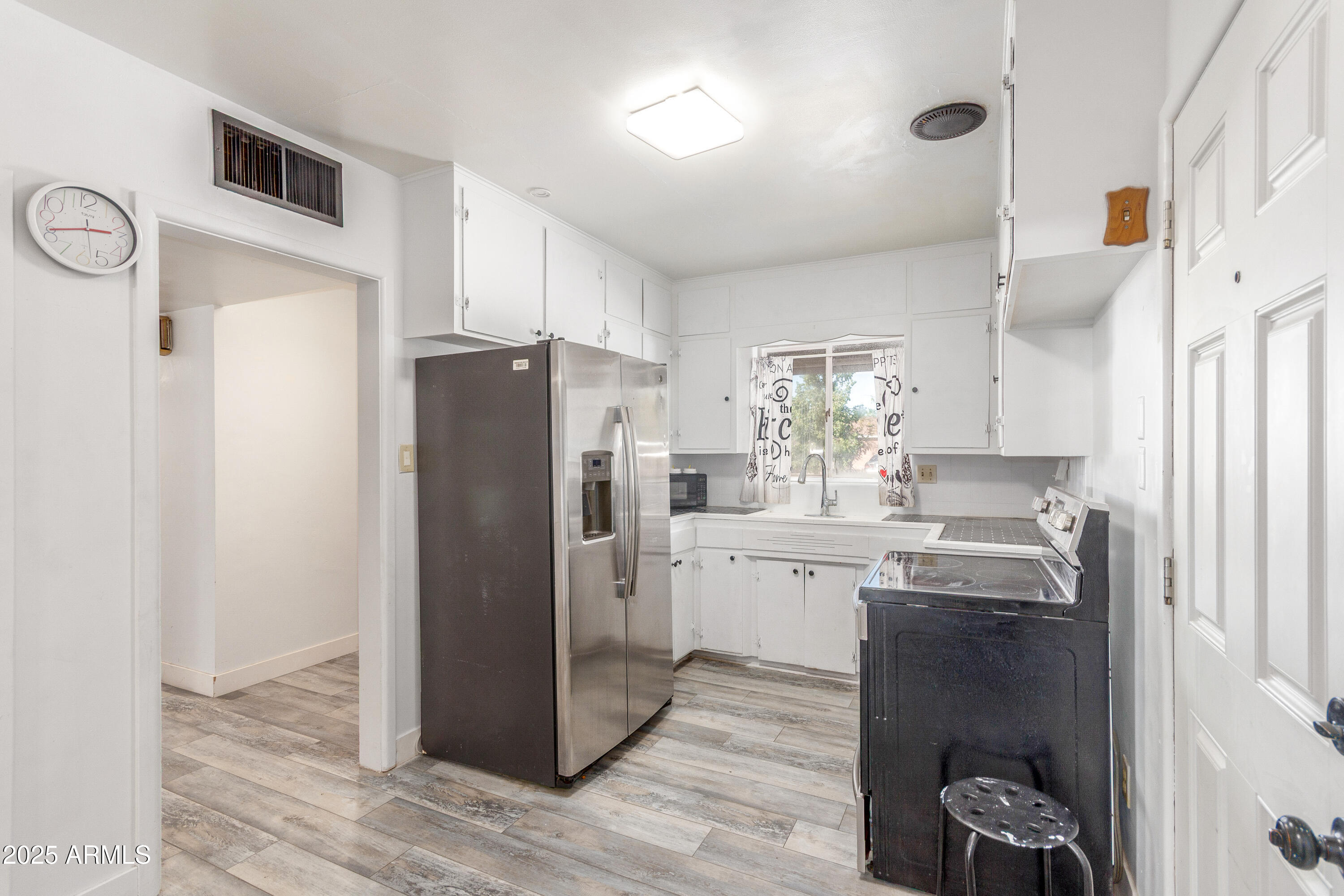 413 East 3rd Street Eloy, AZ 85131 - Photo 13 of 44 a kitchen with stainless steel appliances a refrigerator a sink a stove and white cabinets with wooden floor