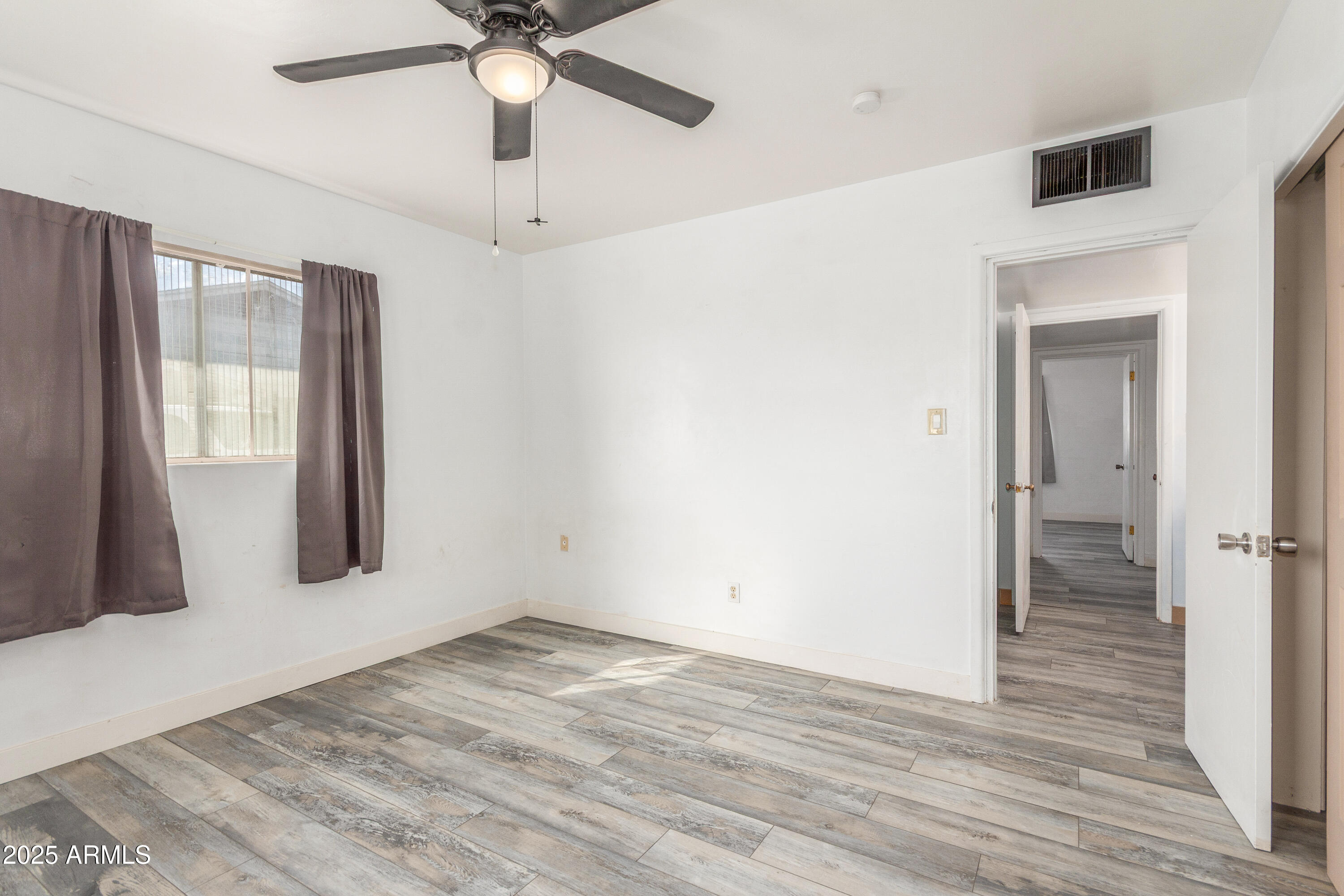 413 East 3rd Street Eloy, AZ 85131 - Photo 21 of 44 a view of an empty room with wooden floor and a window